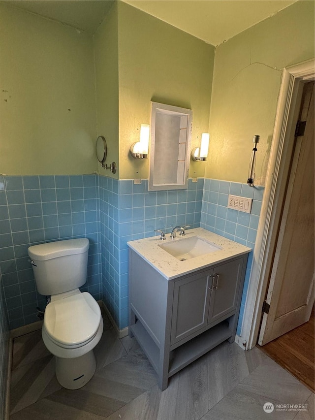 bathroom with tile walls, vanity, and toilet