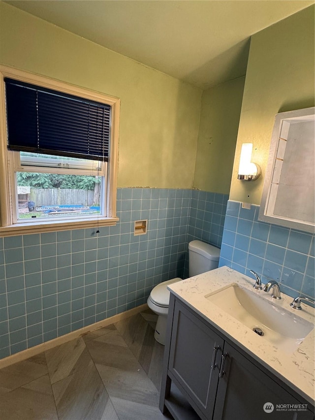 bathroom featuring tile walls, toilet, vanity, and tile patterned floors