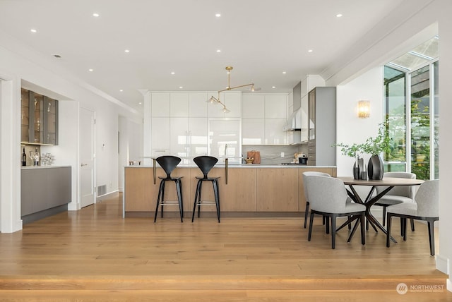 kitchen with white cabinets, light hardwood / wood-style flooring, kitchen peninsula, and tasteful backsplash