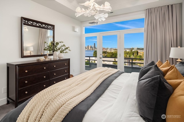 bedroom featuring an inviting chandelier, access to exterior, and a water view