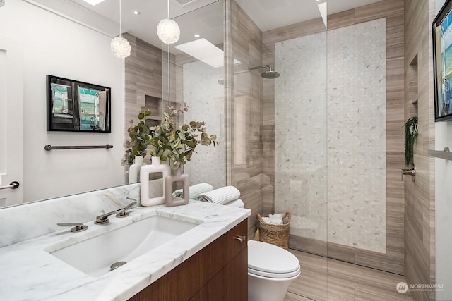 bathroom featuring tiled shower, vanity, and toilet