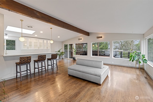 living room featuring vaulted ceiling with skylight and wood-type flooring