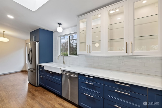 kitchen with tasteful backsplash, decorative light fixtures, dark hardwood / wood-style flooring, appliances with stainless steel finishes, and blue cabinets