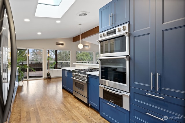 kitchen with blue cabinetry, pendant lighting, appliances with stainless steel finishes, and vaulted ceiling with skylight