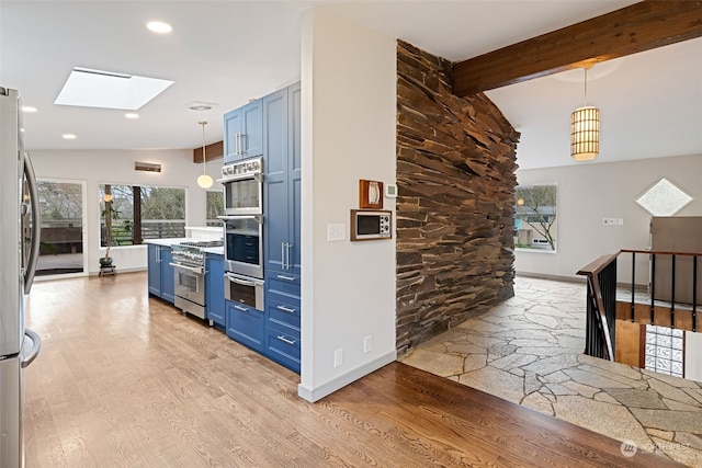 kitchen with decorative light fixtures, beam ceiling, a skylight, appliances with stainless steel finishes, and blue cabinetry