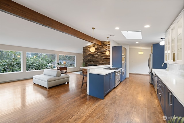 kitchen with a kitchen bar, stainless steel range, a skylight, beamed ceiling, and hanging light fixtures