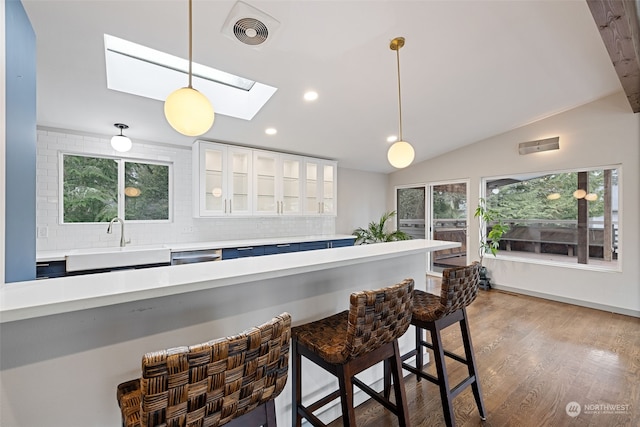 kitchen featuring a kitchen bar, tasteful backsplash, pendant lighting, white cabinets, and sink