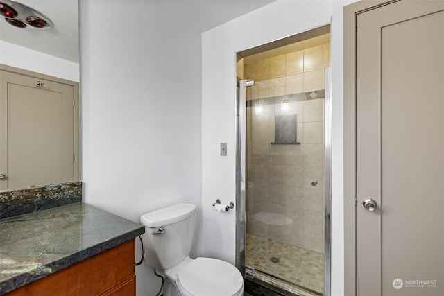 bathroom with a shower with shower door, toilet, and vanity