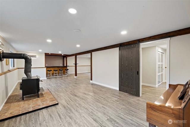 exercise area featuring a wood stove, light hardwood / wood-style flooring, and a barn door