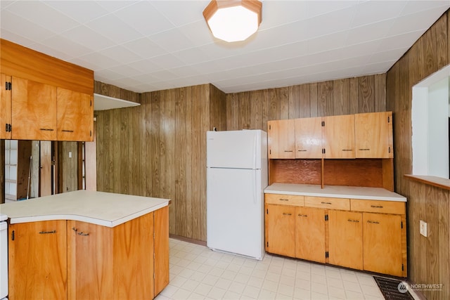 kitchen featuring white fridge, wood walls, and kitchen peninsula