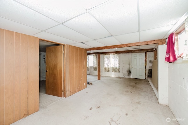 basement with wooden walls and a drop ceiling