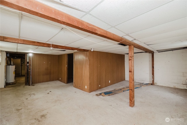 basement featuring a paneled ceiling and water heater