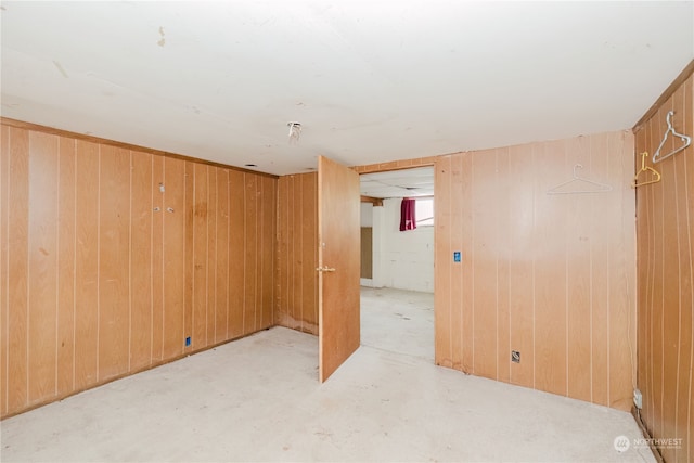 carpeted empty room featuring wood walls