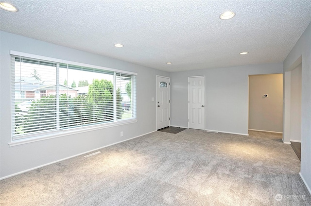 carpeted spare room with a textured ceiling