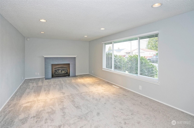 unfurnished living room with a textured ceiling, light carpet, and a fireplace