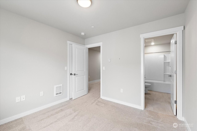 unfurnished bedroom featuring light colored carpet and connected bathroom