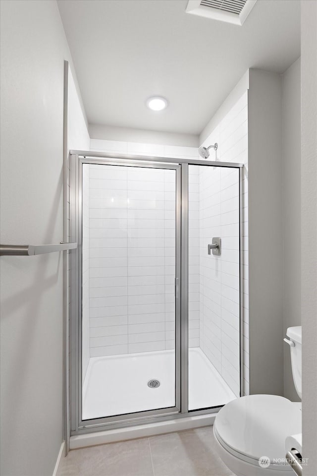 bathroom featuring a shower with shower door, tile patterned floors, and toilet