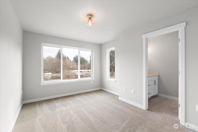 unfurnished bedroom featuring ensuite bathroom and light carpet