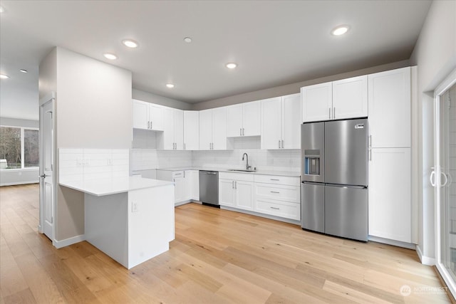 kitchen featuring stainless steel appliances, light hardwood / wood-style flooring, white cabinets, and sink