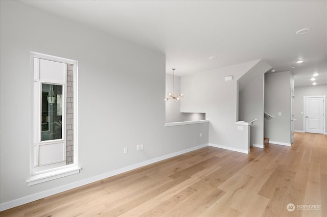 unfurnished living room featuring light wood-type flooring and a chandelier