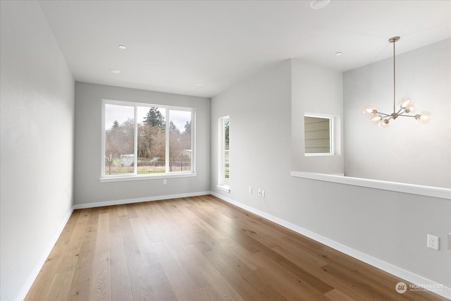 empty room with wood-type flooring and an inviting chandelier