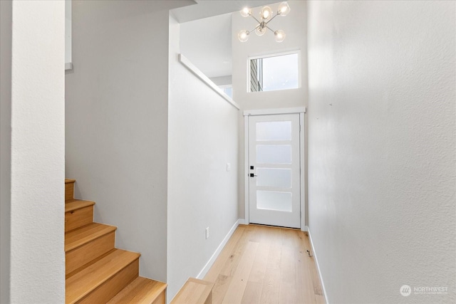 entryway with a towering ceiling, an inviting chandelier, and light hardwood / wood-style floors