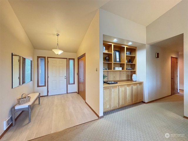 carpeted foyer with lofted ceiling