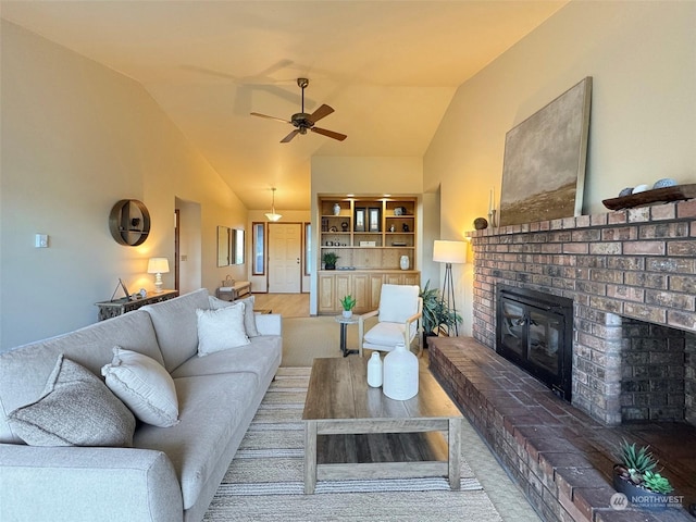 living room with vaulted ceiling, a brick fireplace, and ceiling fan