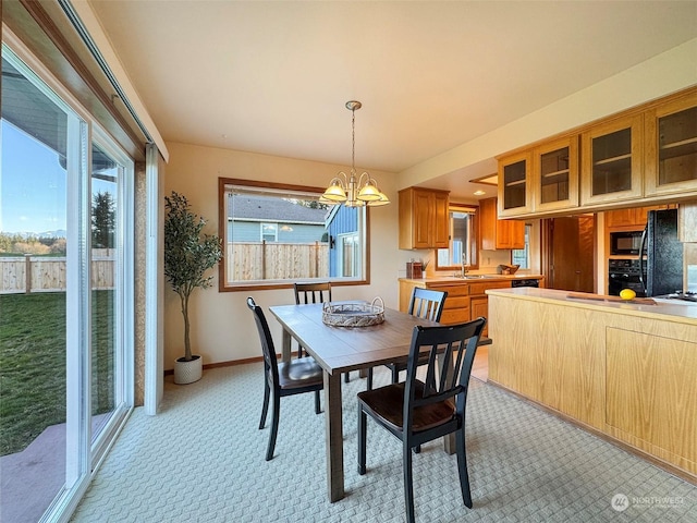 dining space with sink, light colored carpet, and a notable chandelier