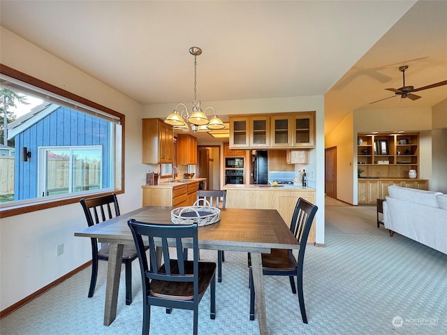 carpeted dining room featuring sink and ceiling fan with notable chandelier