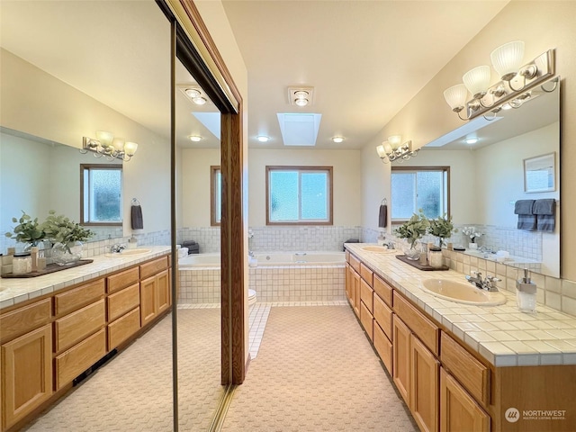 bathroom featuring tile patterned flooring, vanity, a relaxing tiled tub, and an inviting chandelier