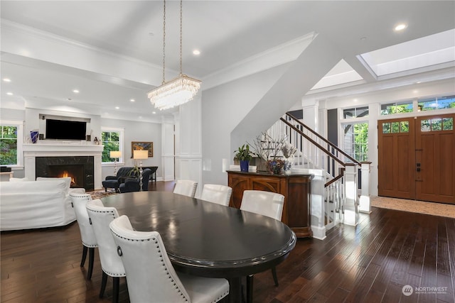 dining room with a premium fireplace, dark hardwood / wood-style floors, crown molding, and plenty of natural light