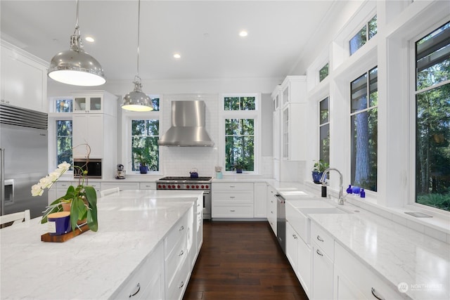 kitchen with light stone countertops, white cabinets, wall chimney exhaust hood, and premium appliances