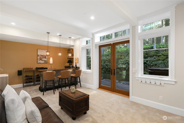 carpeted living room featuring bar area, french doors, and beamed ceiling