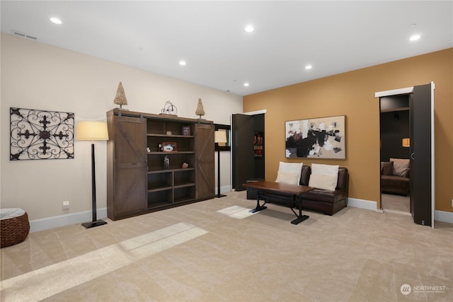 sitting room featuring a barn door and light carpet