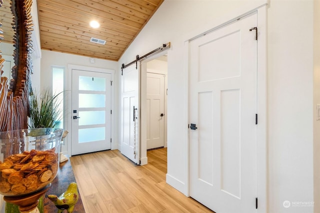 doorway featuring light hardwood / wood-style floors, vaulted ceiling, wooden ceiling, and a barn door