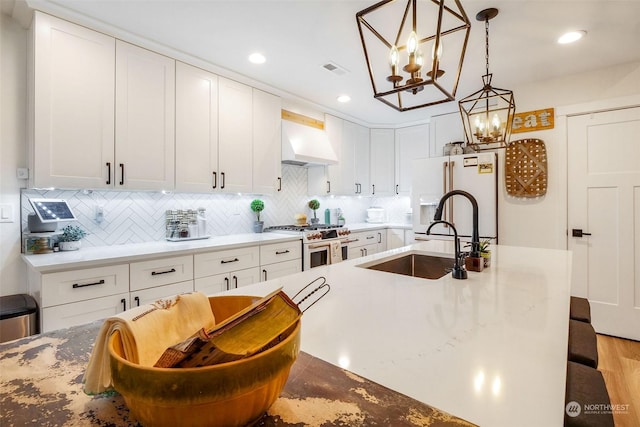 kitchen featuring extractor fan, white cabinets, backsplash, high end range, and white fridge with ice dispenser