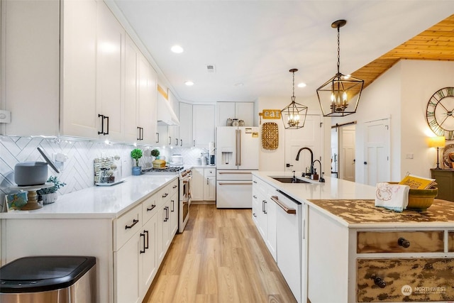 kitchen featuring sink, backsplash, hanging light fixtures, premium appliances, and white cabinets