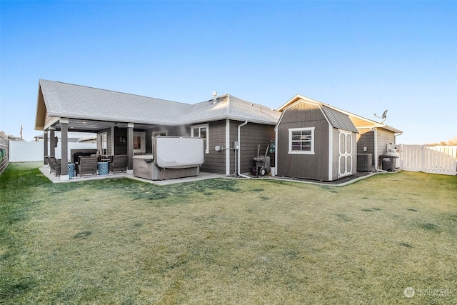 rear view of house with a hot tub, a yard, a shed, and central air condition unit