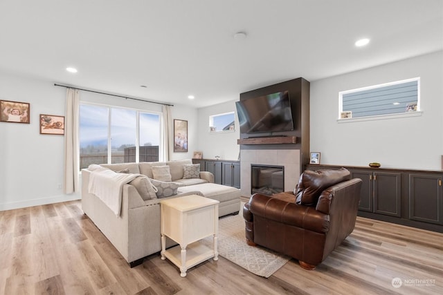 living room with light wood-type flooring and a tile fireplace