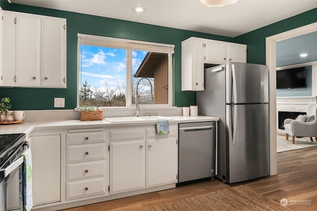 kitchen featuring appliances with stainless steel finishes, sink, white cabinetry, and light hardwood / wood-style flooring