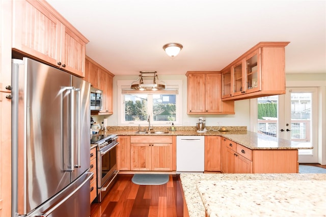 kitchen featuring appliances with stainless steel finishes, kitchen peninsula, light stone countertops, dark hardwood / wood-style flooring, and sink