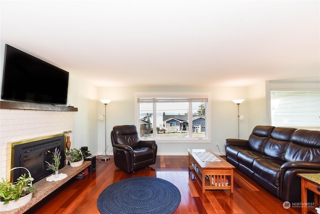 living room with a brick fireplace and dark hardwood / wood-style floors