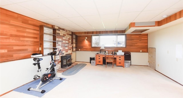 home office featuring a paneled ceiling, wooden walls, and light carpet