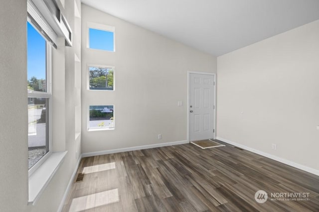 spare room featuring dark hardwood / wood-style floors and high vaulted ceiling