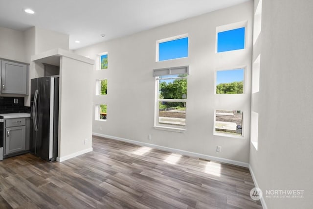 kitchen with gray cabinetry, dark hardwood / wood-style flooring, stainless steel fridge, and tasteful backsplash