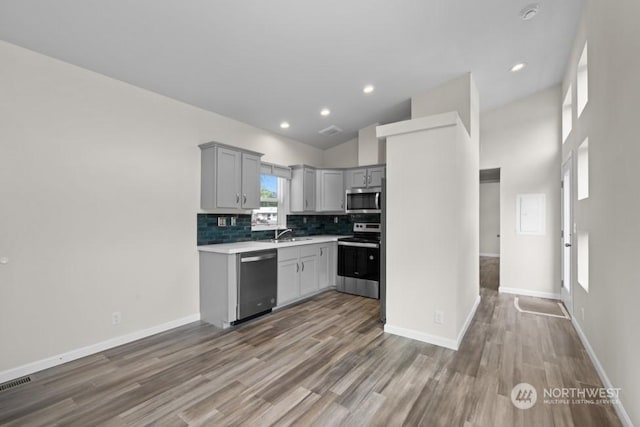 kitchen with gray cabinetry, backsplash, stainless steel appliances, and dark hardwood / wood-style floors