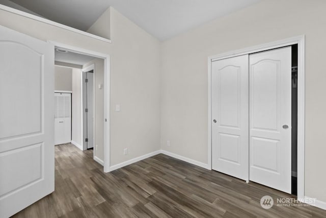 unfurnished bedroom featuring vaulted ceiling, dark hardwood / wood-style flooring, and a closet