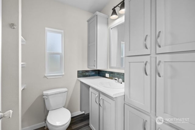 bathroom featuring vanity, hardwood / wood-style floors, decorative backsplash, and toilet