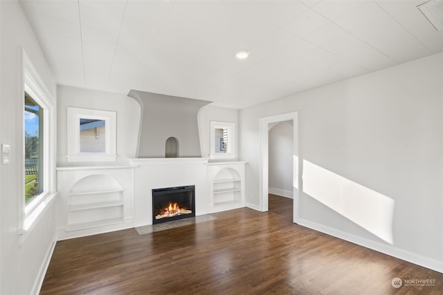 unfurnished living room featuring dark hardwood / wood-style floors and built in shelves